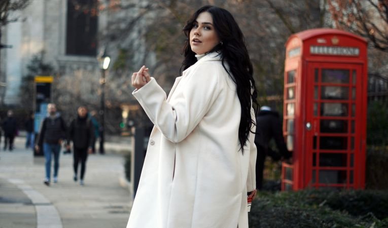 Stylish woman walking London street in white coat